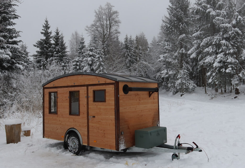 Der kleine Holzwohnwagen im Schnee.